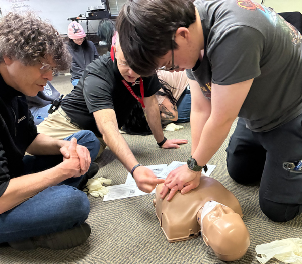 People giving CPR to training doll.